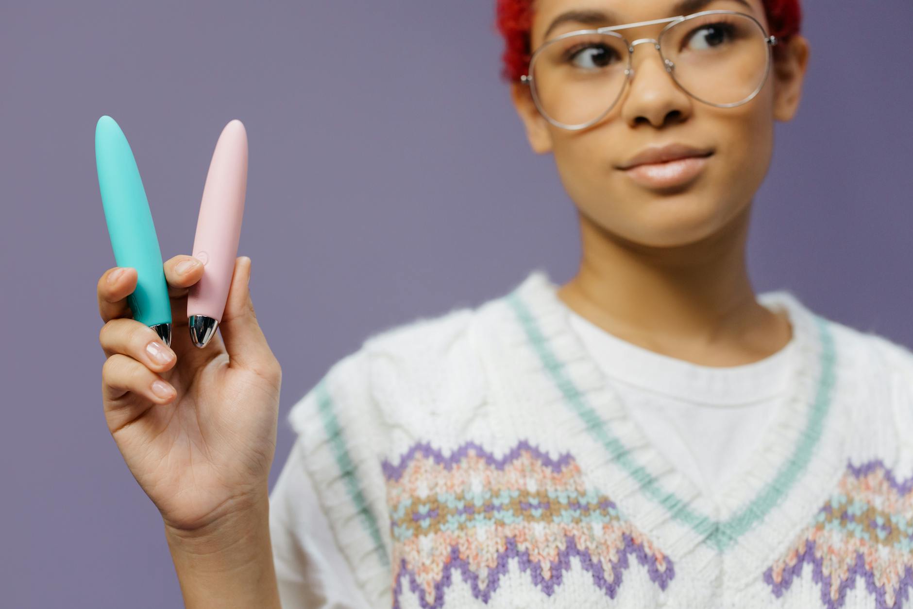 A hand holding a yellow lemon-shaped vibrator against a purple background